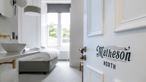 A modern bedroom with a white bed, a bedside table, and a large window. - Matheson North (Isle of Lewis)