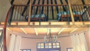 A loft-style room with a high ceiling, wooden beams, and a chandelier.