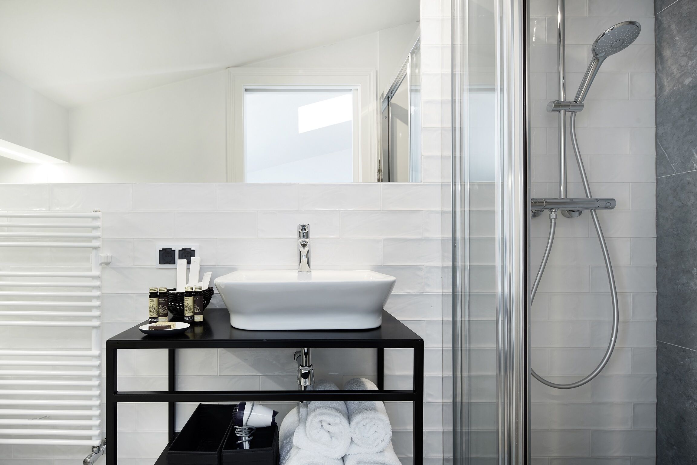 A modern bathroom with a white sink, black vanity, and a glass shower enclosure.