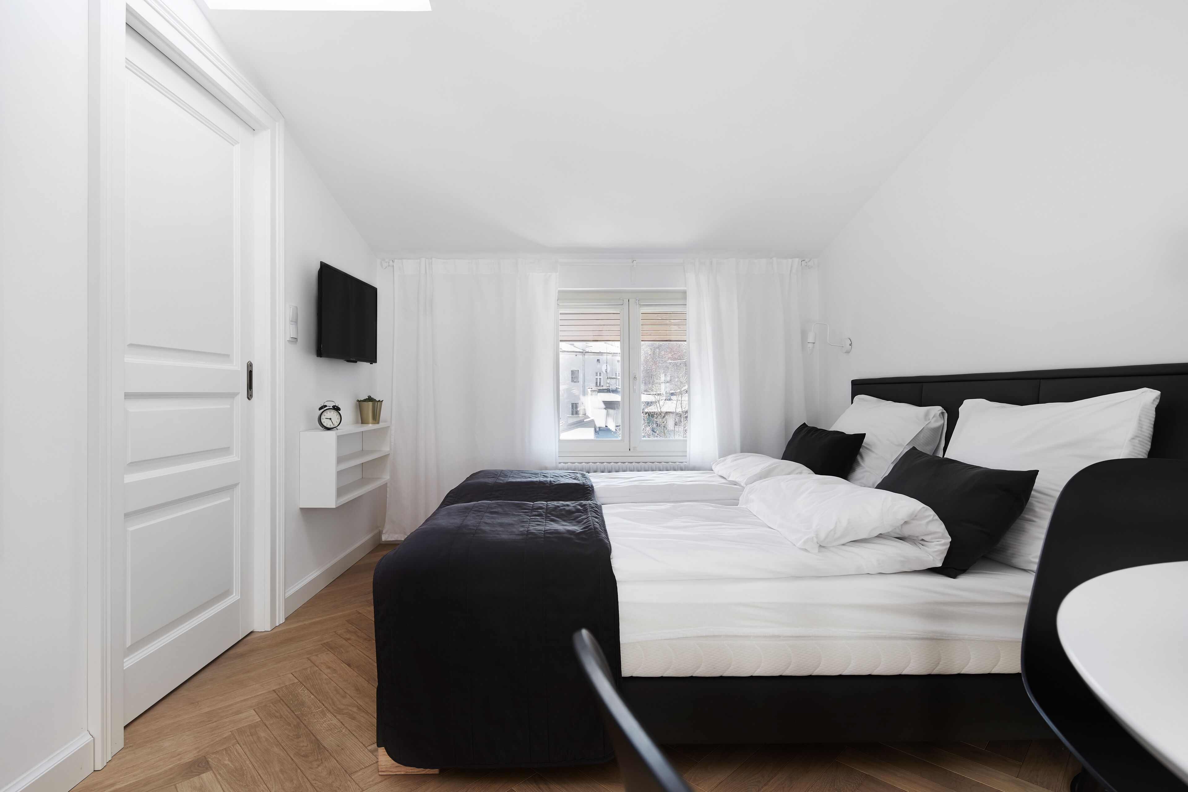 Een moderne hotelkamer met een groot bed, nachtkastje, televisie en raam met gordijnen.