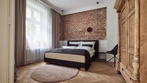 Un dormitorio con pared de ladrillo, cama, armario de madera y alfombra redonda.