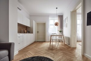 A modern kitchen with white cabinets, a wooden countertop, and a dining area with a table and chairs.