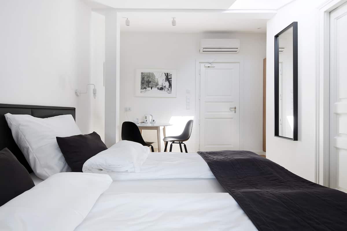 Quarto de hotel com cama, escrivaninha, cadeira e porta.