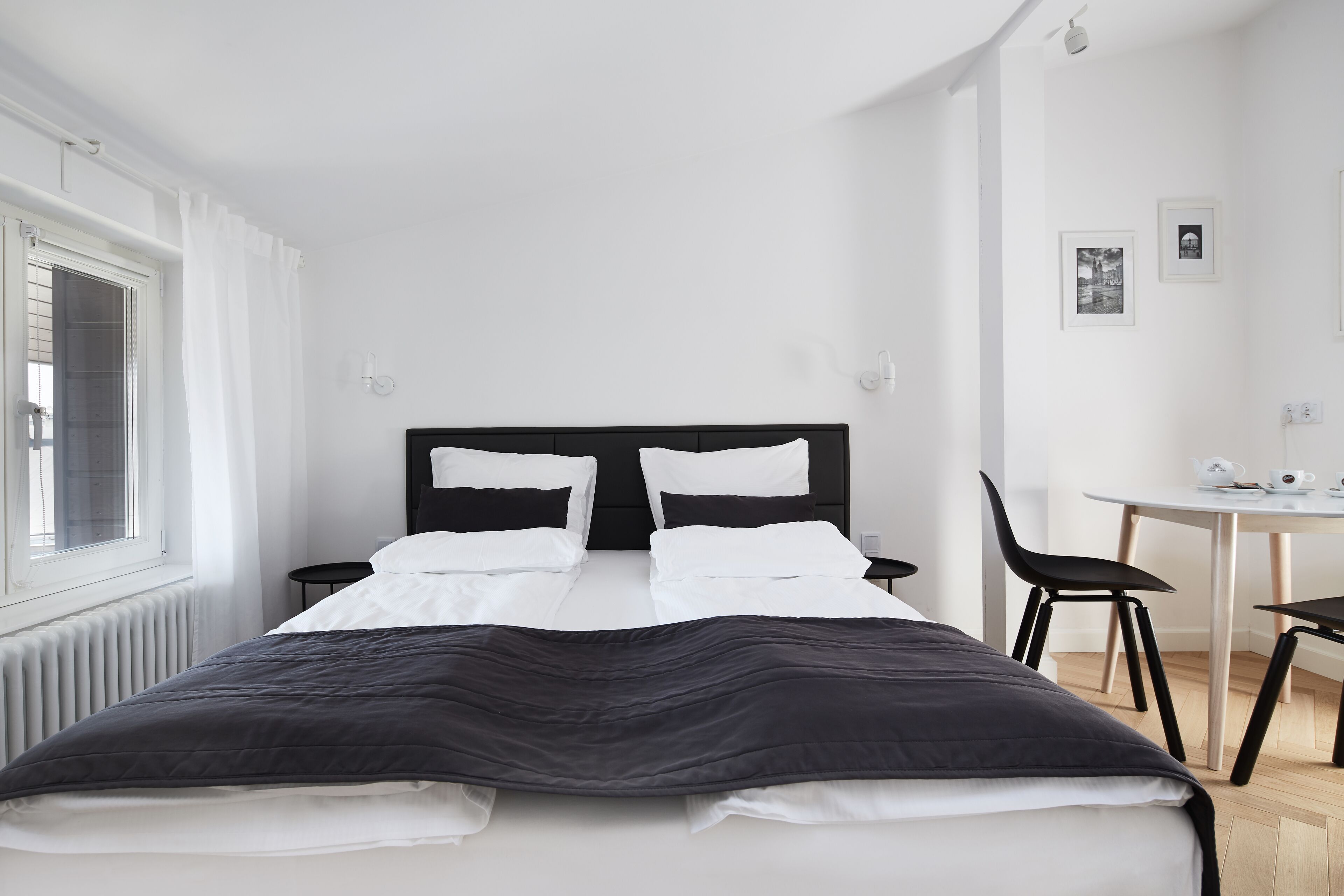 A modern hotel room with a large bed, a small table, and two chairs.