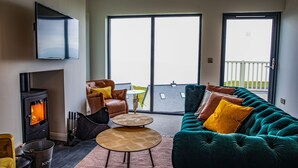 Ein modernes Wohnzimmer mit Kamin, einer Couch, einem Couchtisch und einem an der Wand befestigten Fernseher.