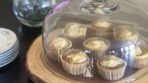 A glass dome over cupcakes on a wooden board. - Franklin Manor Bed & Breakfast (Saranac Lake)