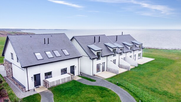 Un moderno edificio residencial con varias unidades, un cimiento de piedra y vista al mar.