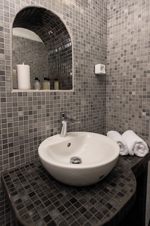 Ein Badezimmer mit einem weißen Waschbecken, einem Spiegel und einem Handtuchhalter.