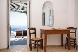 Ein Zimmer mit Holztisch und -stühlen, einem Fenster mit Aussicht und einer Tür zu einem Außenbereich.