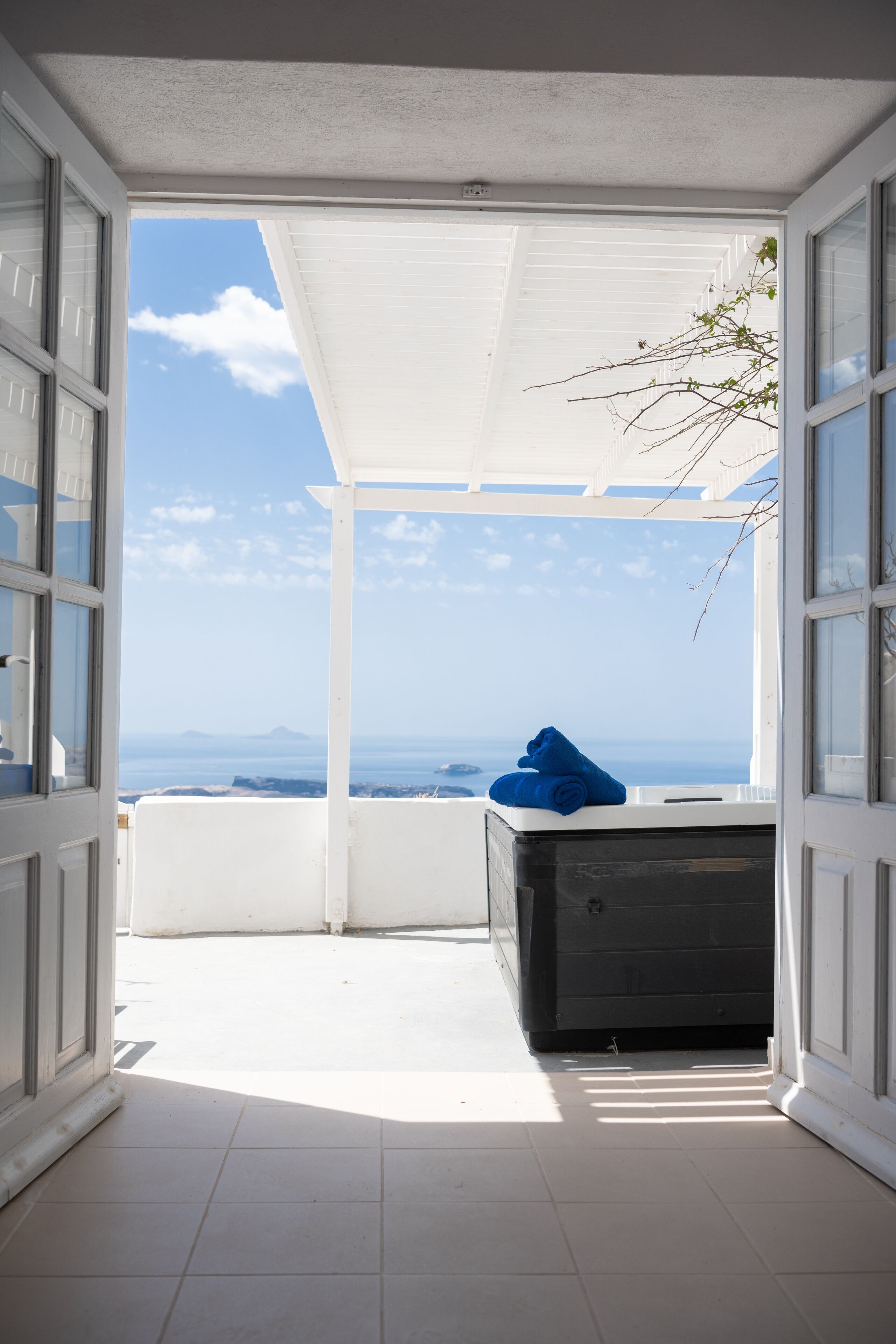An open balcony with a view of the sea and mountains, a white ceiling, and a black object on the floor.