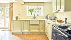 A kitchen with a large island, a window with a view, and a vintage stove. - Coach House (Totnes)