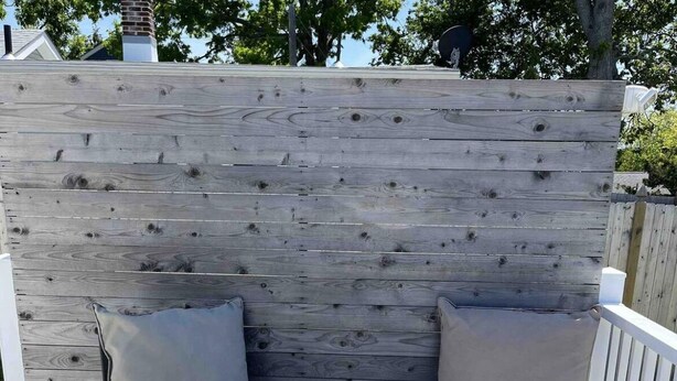 Een houten terras met twee beige fauteuils en een kleine tafel.