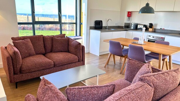 Een moderne woonkamer met een bank, een salontafel en een eethoek met stoelen en een tafel.