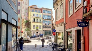 Una calle adoquinada flanqueada por edificios, una señal de parada y un cartel direccional azul.