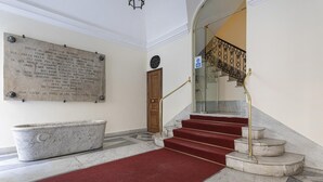 A marble staircase with red carpeted steps and a golden handrail, leading to an upper floor. - Cairoli Stylish Apartment by Wonderful Italy (Genoa)