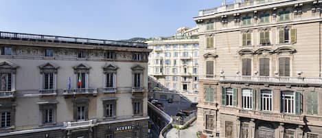 A street view with buildings featuring classical architecture, including ornate balconies and decorative window frames.