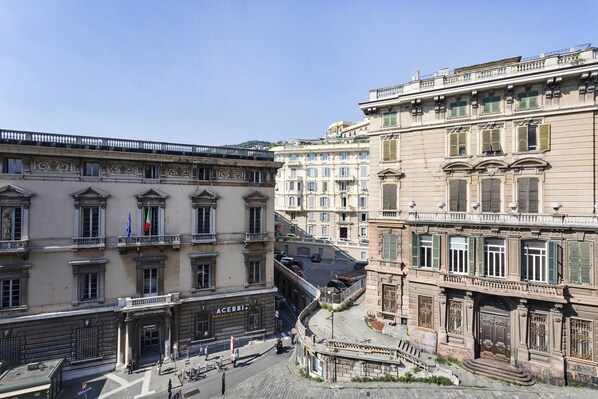 A street view with buildings featuring classical architecture, including ornate balconies and decorative window frames.