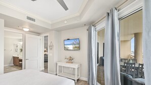 Una camera da letto con un letto, un comodino, una TV e vista sul balcone.