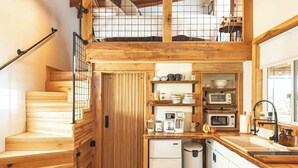 A wooden interior with a staircase, kitchen area, and a dog.