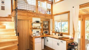 A cozy cabin-style interior with a kitchen, dining area, and a green sofa.