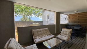 A balcony with wicker chairs and a small table, overlooking a stone wall and a tree. - T3 Bord Canal du Midi Piscine (Homps)