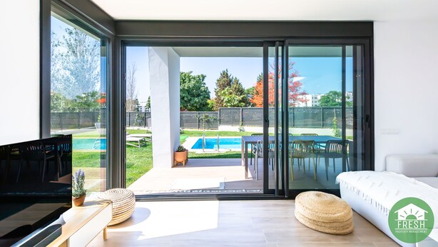 A modern living room with a large sliding glass door leading to an outdoor patio area.