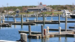 A marina with multiple docks and boats, a large building with a red roof, and a grassy area in the background. - 2 John Ewer Rd (Sandwich)