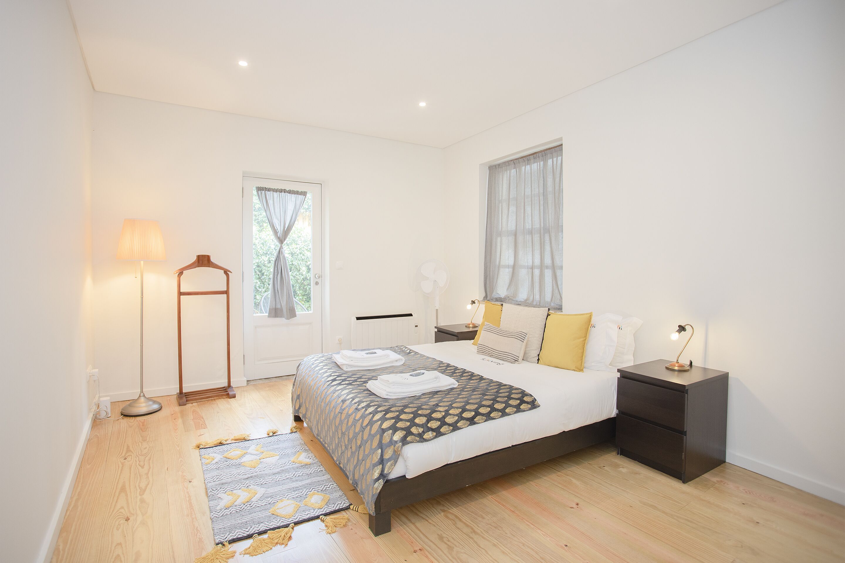 A bedroom with a bed, bedside tables, a floor lamp, and a window with curtains.