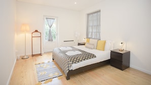 A bedroom with a bed, bedside tables, a floor lamp, and a window with curtains. - Liiiving - Oasis Retreat Apartment (Porto)