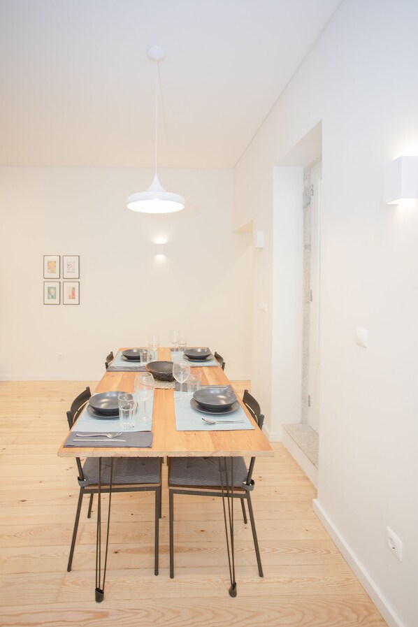 A dining area with a wooden table set for four, chairs, and a hanging light fixture.