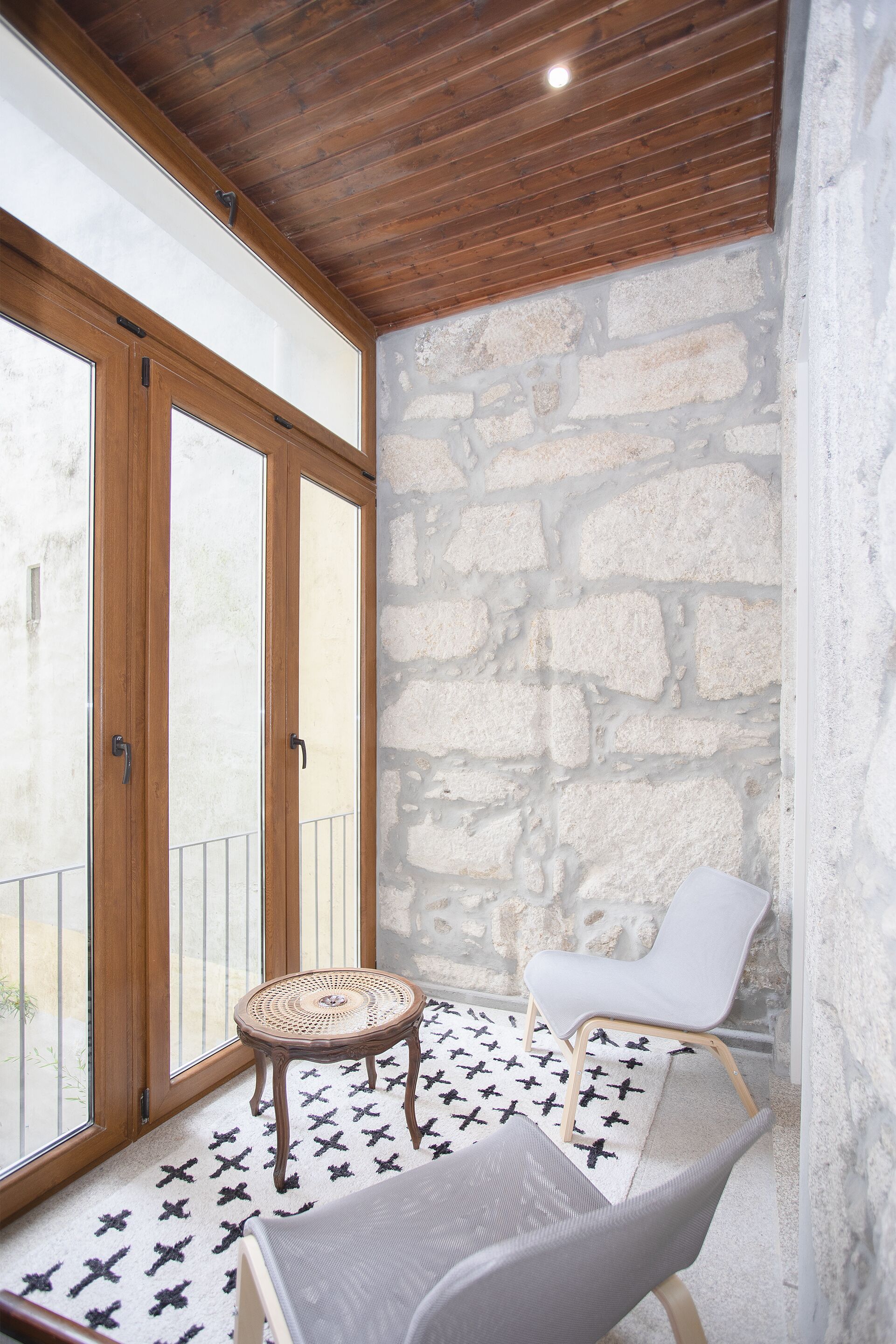 A room with a stone wall, a wooden ceiling, and a large window with a view.