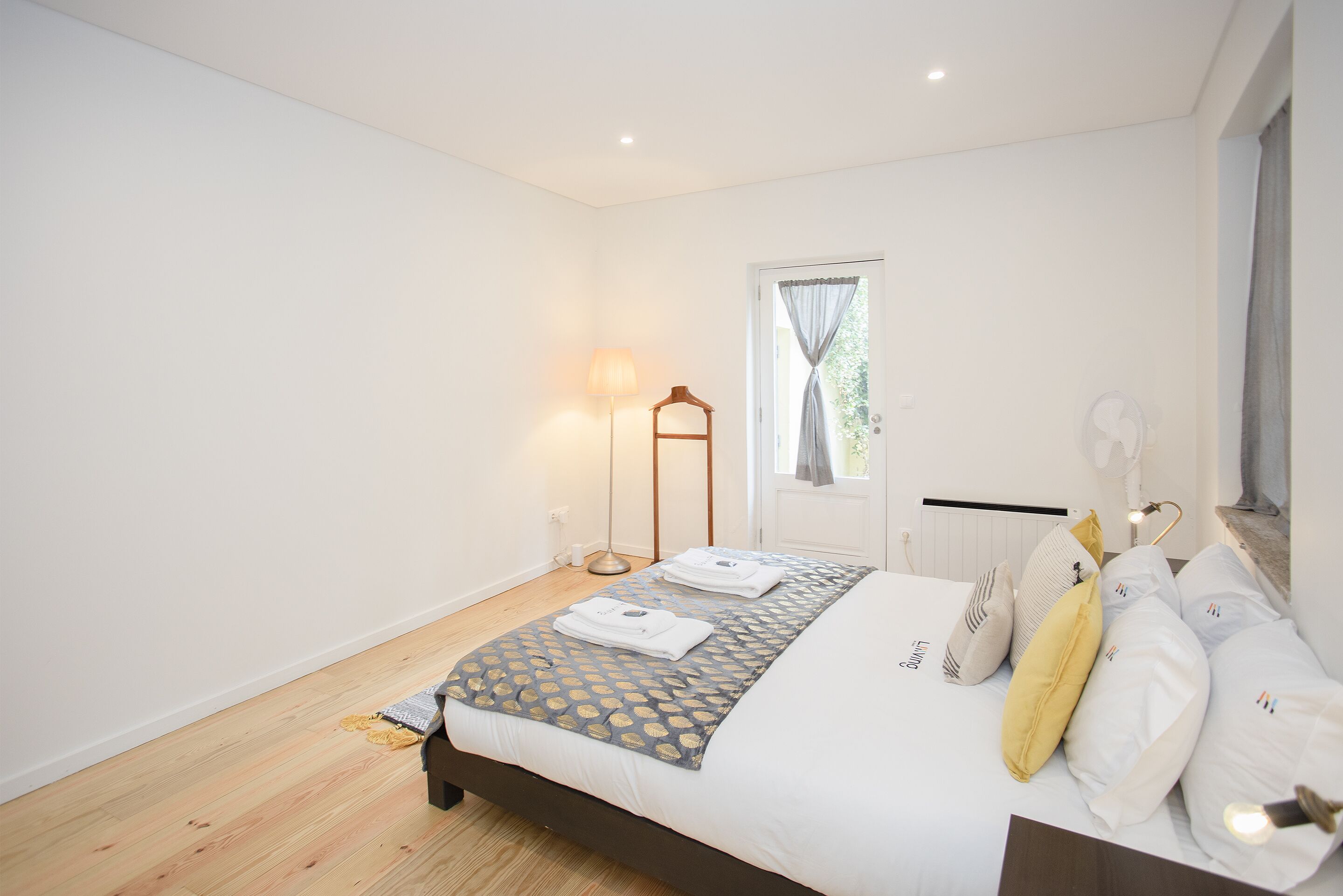 A bedroom with a bed, bedside table, lamp, and window with curtains.
