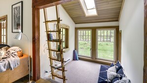 Une chambre avec un lit en mezzanine, une lucarne, une grande fenêtre et une échelle en bois.