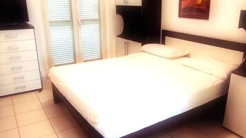 Una camera da letto con un letto, una cassettiera, una TV e un quadro appeso al muro.