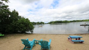 Una playa con sillas Adirondack turquesa y mesas de picnic.