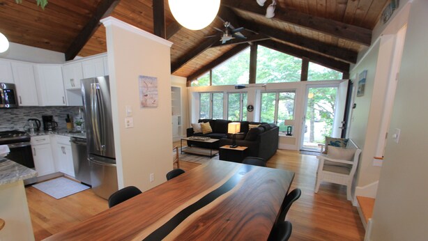 Una cocina moderna con armarios blancos, un refrigerador de acero inoxidable y una mesa de comedor de madera.