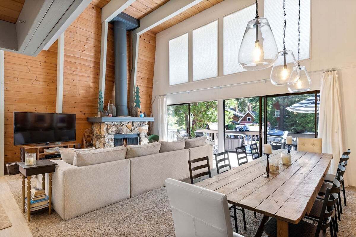 Een ruime woonkamer met een grote bank, een houten eettafel en een televisie.