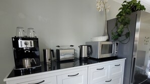 Eine Küche mit Kaffeemaschine, Toaster, Wasserkocher, Mikrowelle und Kühlschrank.
