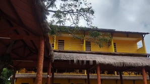 Un edificio de dos pisos con paredes amarillas y techo de paja.
