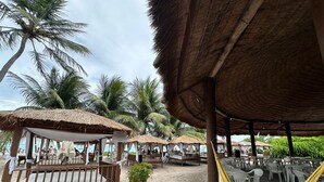 Un resort frente a la playa con estructuras de techo de paja, asientos al aire libre y hamacas.