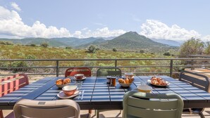 A dining table set with food and drinks, overlooking a mountainous landscape. - Villa Lurenzu - Maison pour 8 avec piscine (Belgodère)
