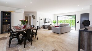 Ein modernes Wohnzimmer mit Essbereich, einem grauen Sofa und einem Fernseher.