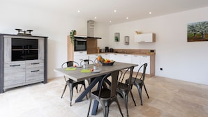 A modern kitchen with a dining area, featuring a wooden table, chairs, and a built-in oven.