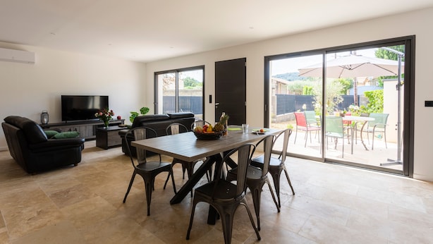 A spacious living area with a dining table, chairs, a sofa, and a TV.