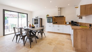 A modern kitchen with white cabinets, a wooden countertop, and a dining area with a table and chairs.