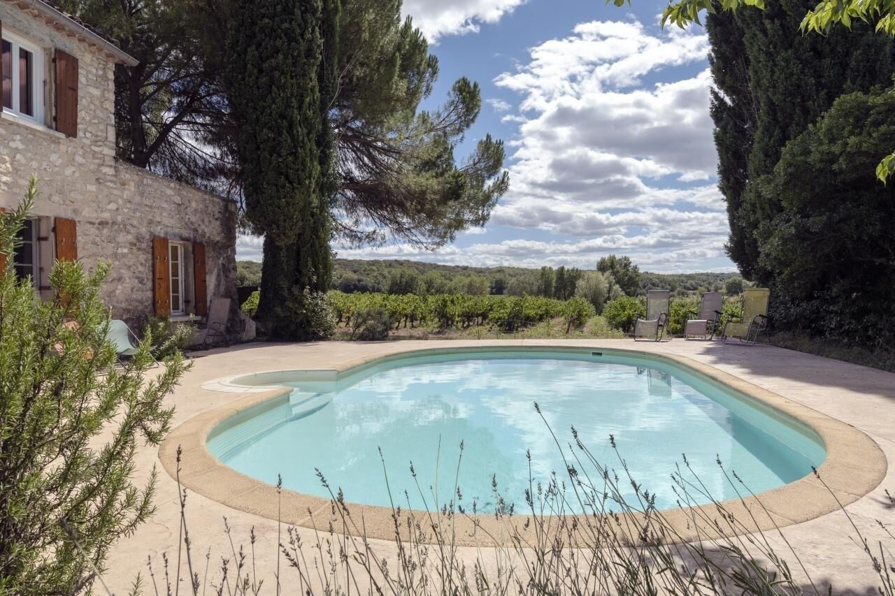 A swimming pool surrounded by a stone building with large windows and a view of the countryside.