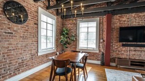 Een eetruimte met een bakstenen muur, een houten tafel en stoelen.