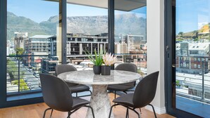 A modern dining area with a marble table, black chairs, and potted plants. - Docklands 502 (Cape Town)