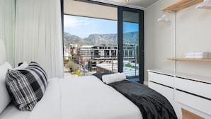 A modern hotel room with a large bed, a view of the cityscape, and a balcony with a mountain backdrop. - Docklands 502 (Cape Town)