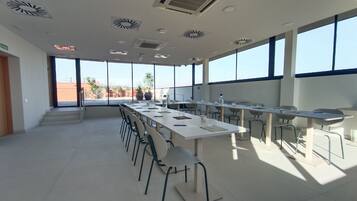 A spacious conference room with a long table, chairs, and large windows.